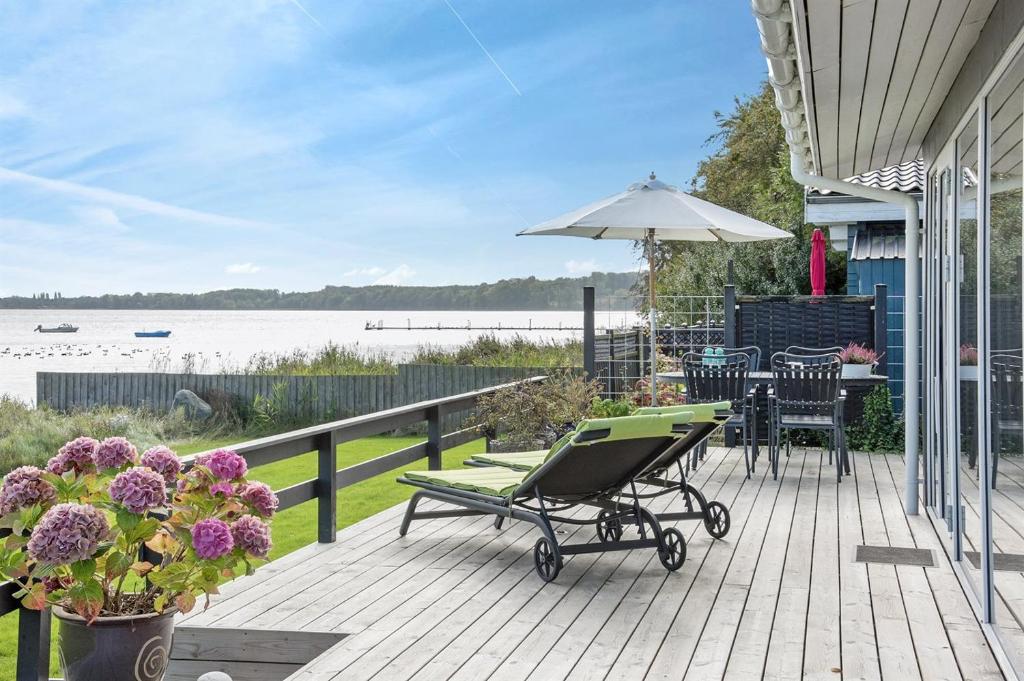 een terras met een stoel, een tafel en een paraplu bij Eksklusiv feriebolig med panoramaudsigt in Munkebo