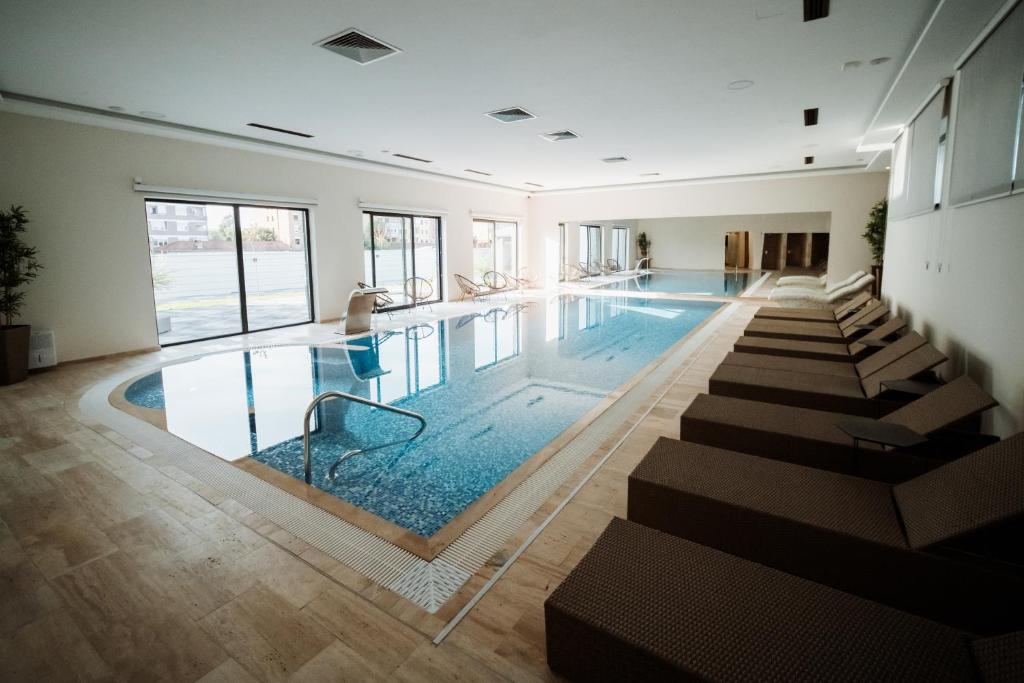 a large swimming pool with chairs in a building at Hotel Barcode Wellness & Spa in Sombor