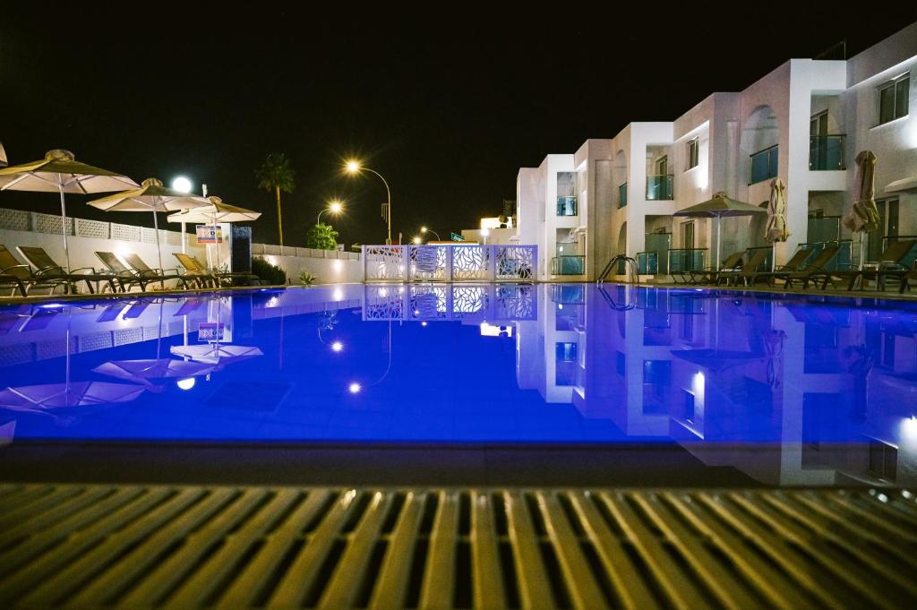 a large swimming pool at night with buildings at Kaos Hotel Apartments in Ayia Napa