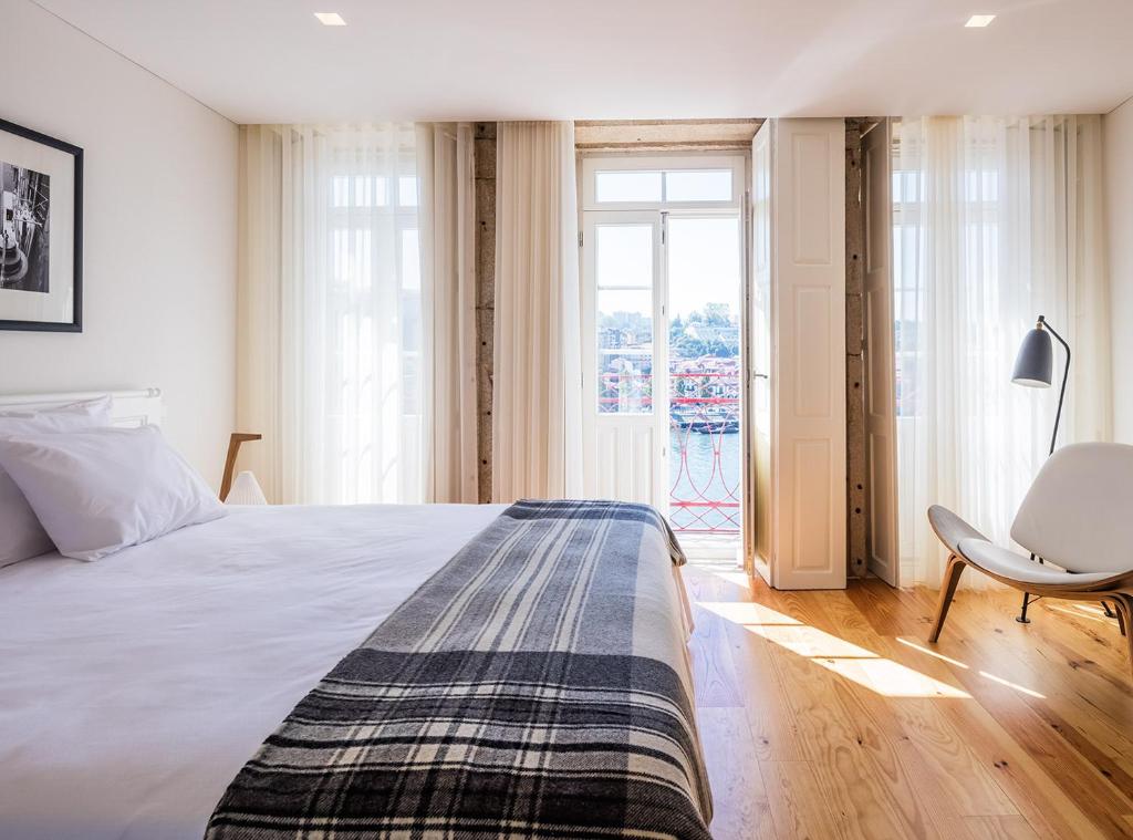 um quarto com uma cama, uma cadeira e uma janela em Porto River no Porto