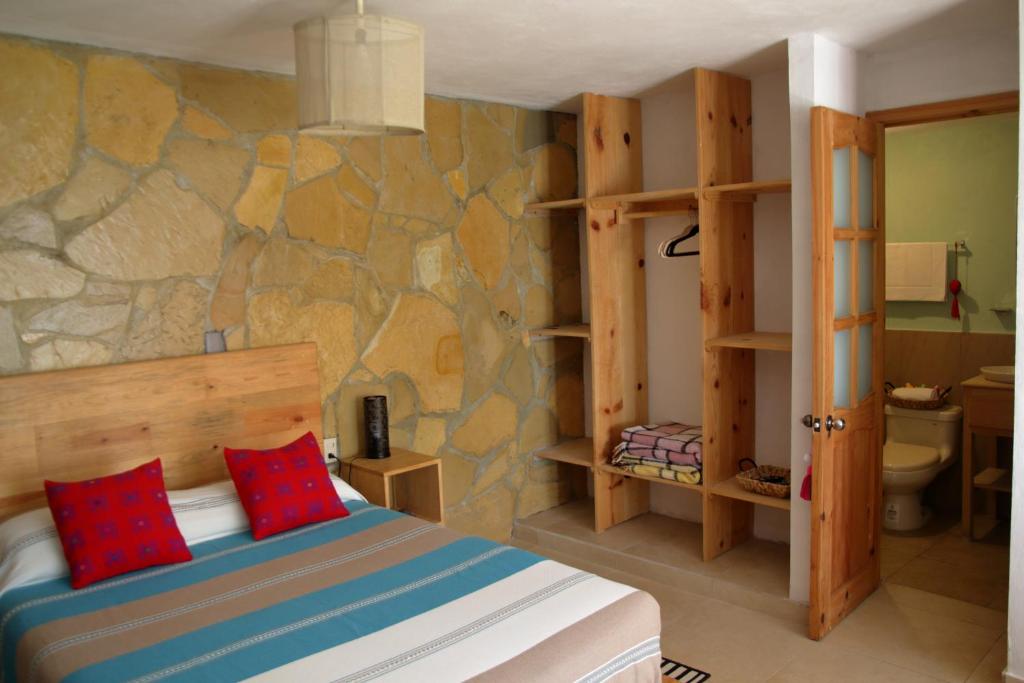 a bedroom with a bed and a stone wall at Gaia Guest House in San Cristóbal de Las Casas