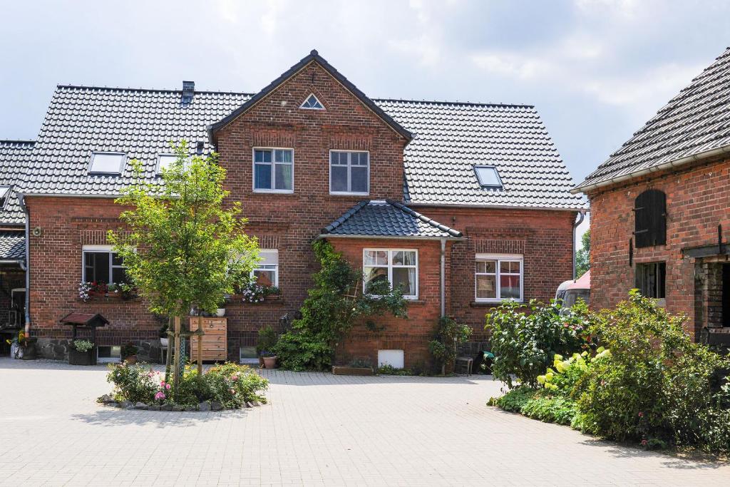 a brick house with a tree in a courtyard at Gutshof Zum Adlernest in Arnsnesta