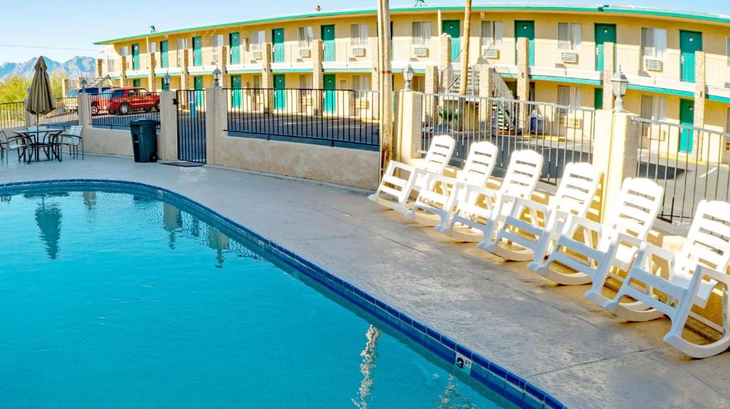 a pool with chairs and a building in the background at Windsor Inn Lake Havasu City in Lake Havasu City