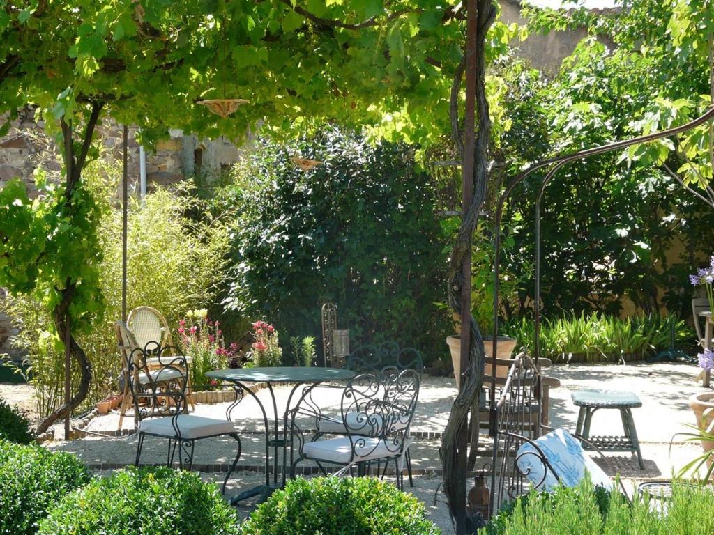 um pátio com uma mesa e cadeiras num jardim em Lou Amourie em Roussillon