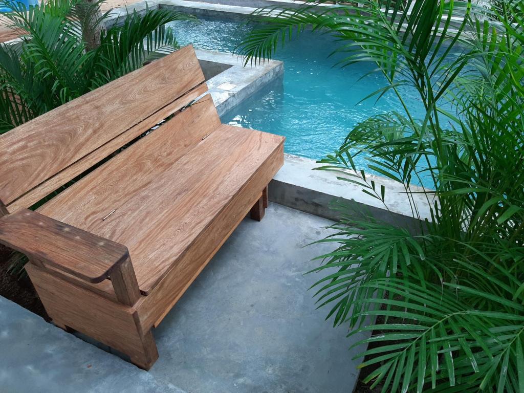 um banco de madeira ao lado de uma piscina em Soiree em Zipolite
