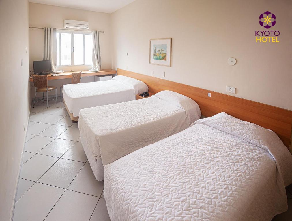 Habitación hospitalaria con 3 camas y escritorio en Kyoto Hotel, en São Paulo