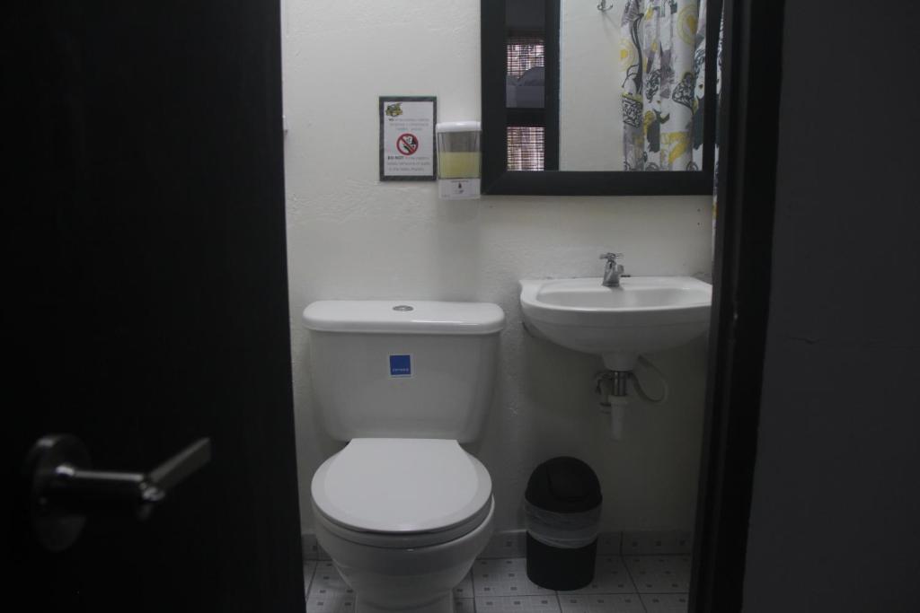a bathroom with a white toilet and a sink at Eden`s Garden Hostel in Panama City