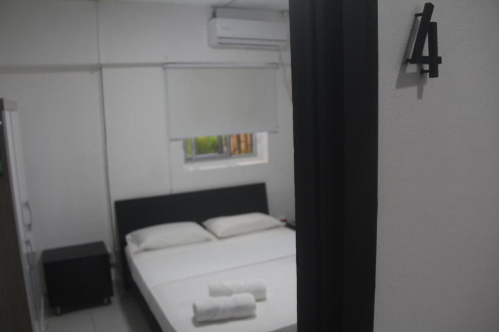 a bedroom with a bed with white sheets and a mirror at Eden`s Garden Hostel in Panama City