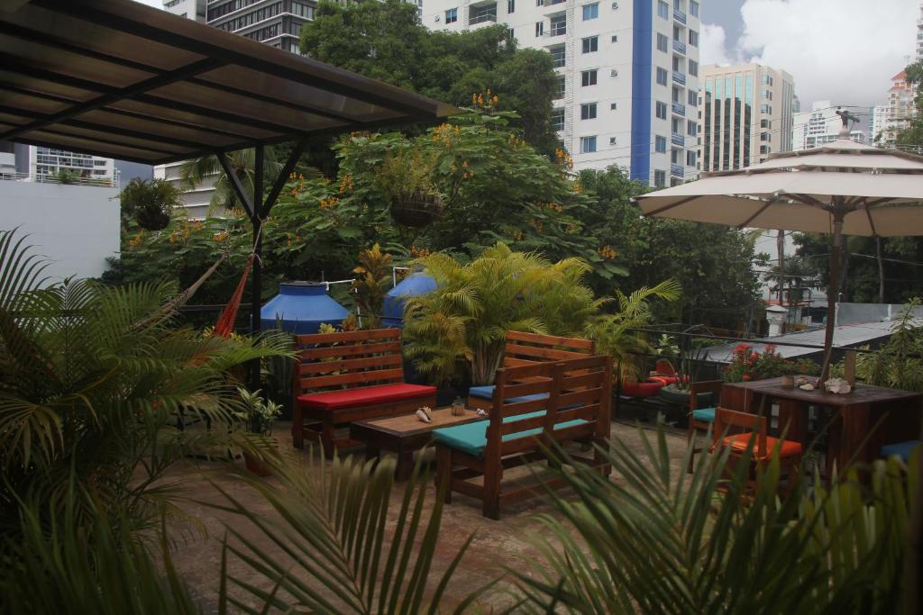 a patio with chairs and tables and an umbrella at Eden`s Garden Hostel in Panama City