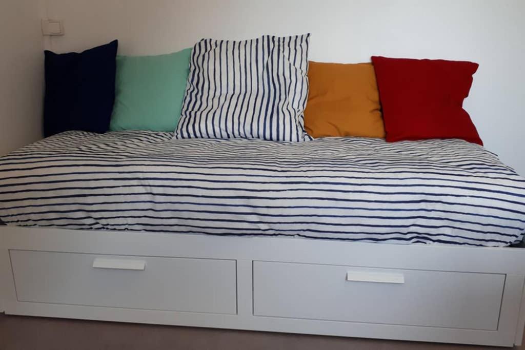 a bed with colorful pillows on top of it at STUDIO Cosy et fonctionnel, proche de Paris in Villeneuve-la-Garenne
