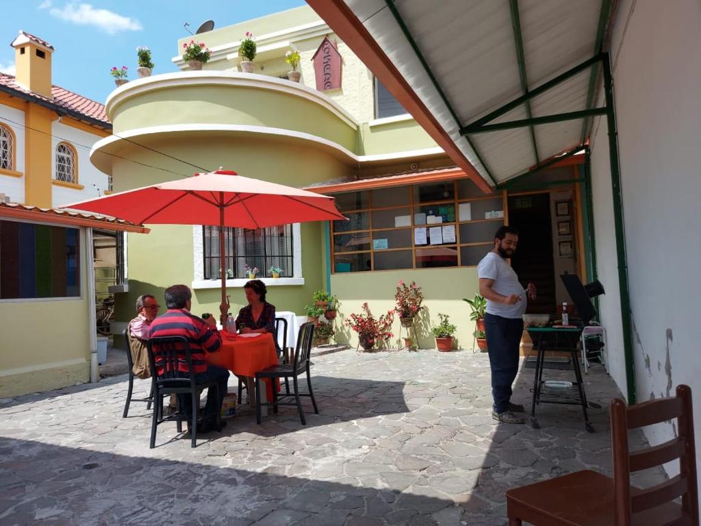 un grupo de personas sentadas en una mesa bajo un paraguas en Posada Tambuca, en Quito