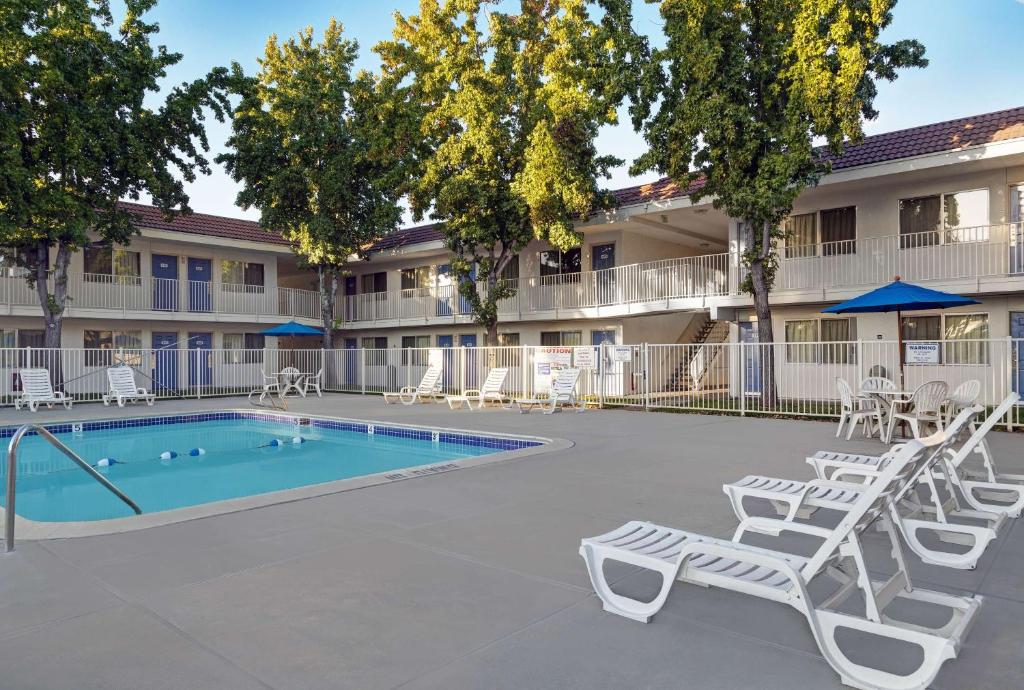 une cour avec une piscine et des chaises ainsi qu'un bâtiment dans l'établissement Motel 6-San Jose, CA - South, à San José