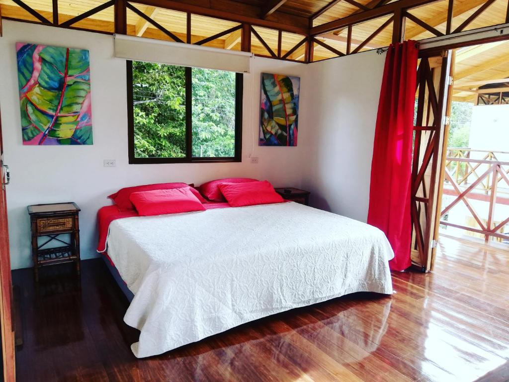 1 dormitorio con cama blanca y almohadas rojas en Ibiza Tropical Beach Villas en Uvita