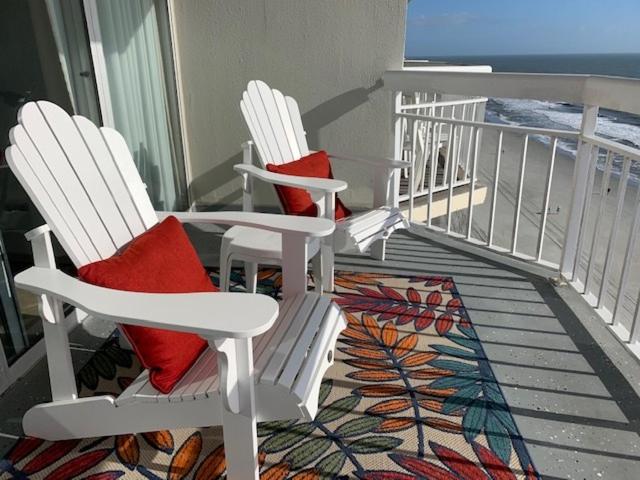 two white chairs with red pillows sitting on a balcony at 1004 Waters Edge Resort condo in Myrtle Beach