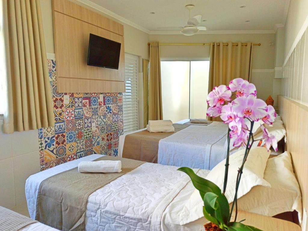 um quarto de hotel com duas camas e uma flor em Hotel Pousada Família de Nazaré em Cachoeira Paulista
