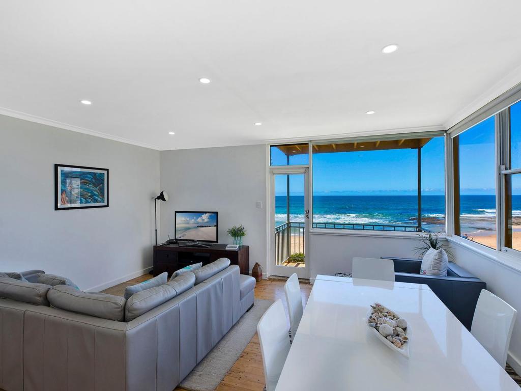 a living room with white furniture and a view of the ocean at Golden Sands 1 - Absolute Beachfront in Blue Bay 