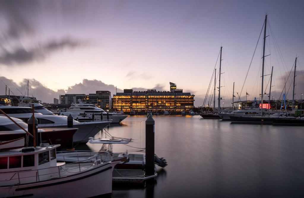 オークランドにあるPark Hyatt Aucklandの一団の船が港に停泊し、建物を持つ