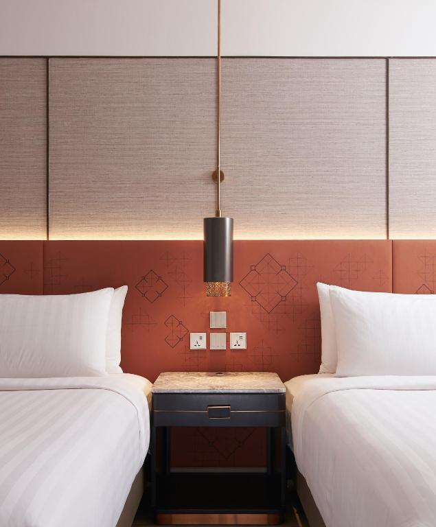 a room with two beds and a table between them at Amari Bangkok in Bangkok