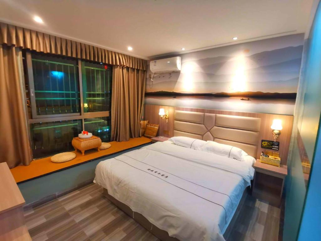 Un dormitorio con una gran cama blanca y una ventana en Jieyang Yunduo Hotel (Chaoshan Airport) en Jieyang