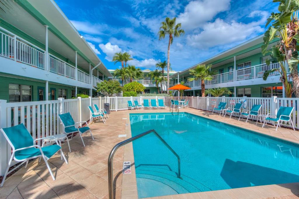 einen Pool in einem Resort mit blauen Stühlen und Palmen in der Unterkunft Tropic Terrace #9 - Beachfront Rental condo in St Pete Beach