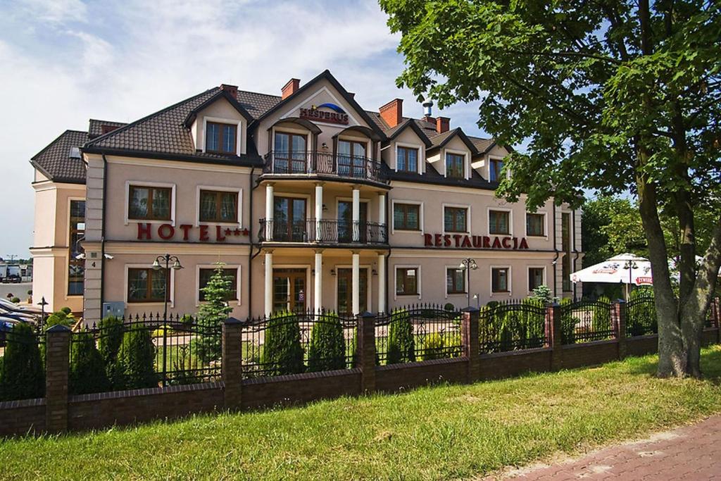 uma casa branca com uma cerca à frente. em Hotel Hesperus em Miedzyrzec Podlaski
