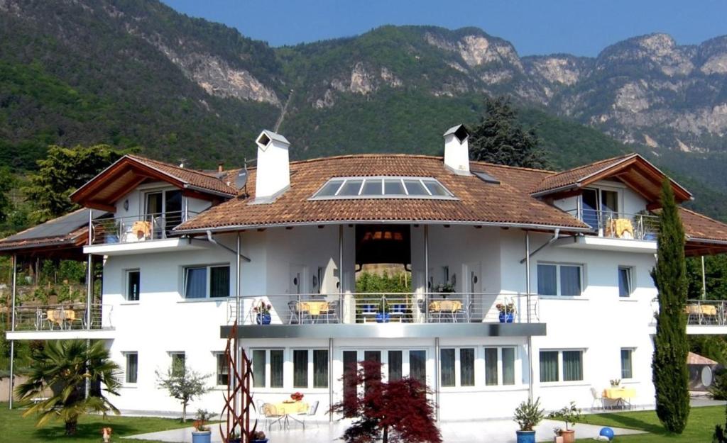 una grande casa bianca con montagne sullo sfondo di Millenniumshof a Caldaro