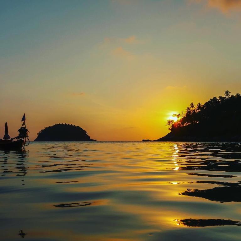 a person in a boat on the water at sunset at The Mantra Hotel Kata Noi in Kata Beach