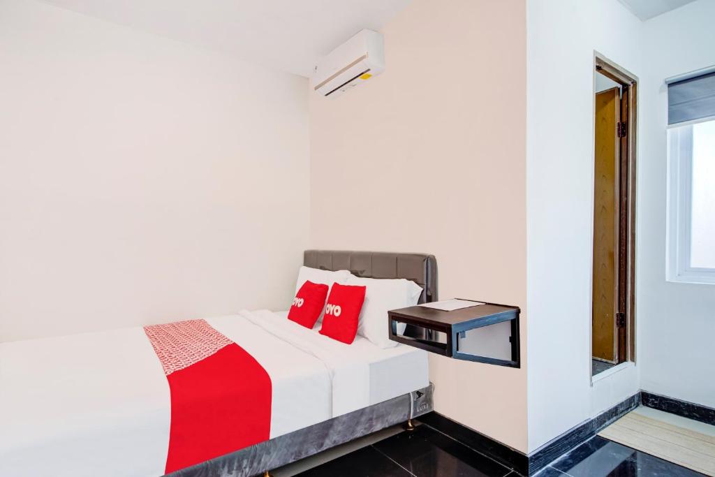 a bedroom with a bed and a window at Super OYO Capital O 3198 Sukomanunggal Inn in Surabaya