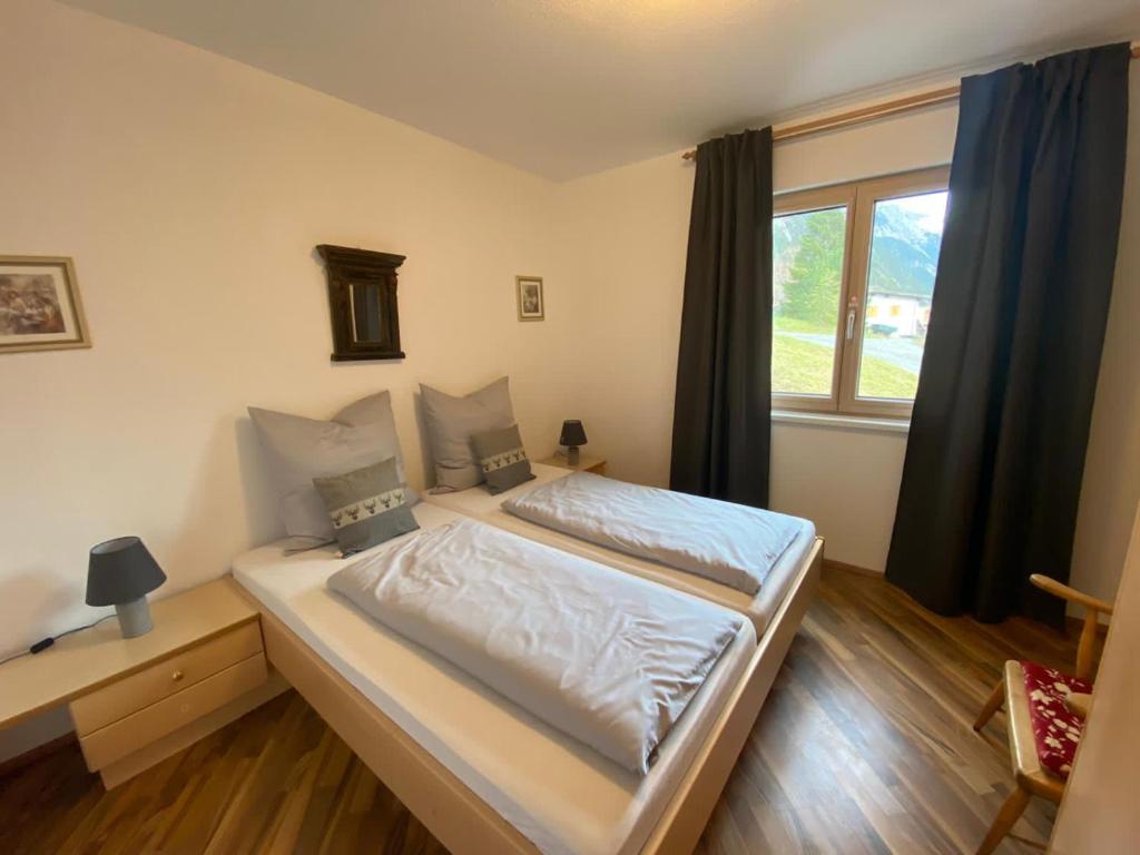 Cette chambre comprend un grand lit et une fenêtre. dans l'établissement Appartement Klein Tirol, à Pettneu am Arlberg