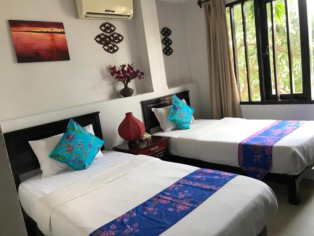 1 dormitorio con 2 camas y almohadas azules en Vientiane SP Hotel, en Vientiane