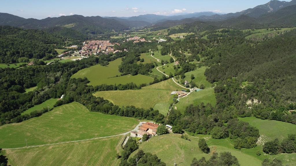 an aerial view of a valley with green fields and trees at La Batllia in Sant Joan de les Abadesses