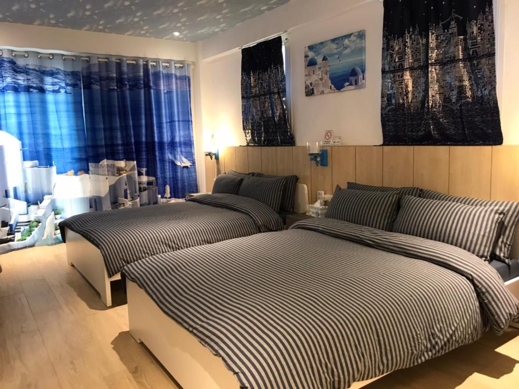 2 letti in una camera da letto con tende blu di Blue House a Jincheng