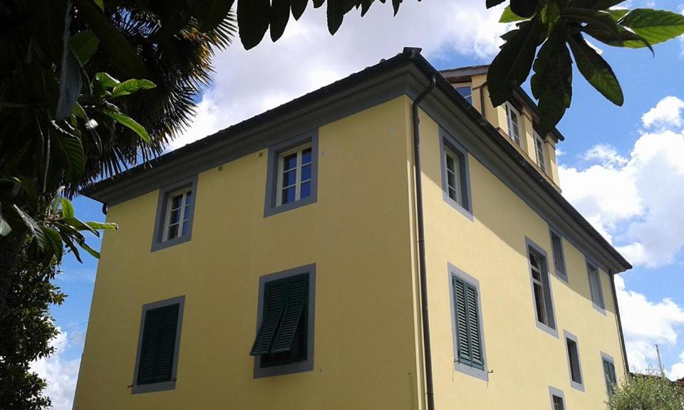 żółty budynek z czarnymi okiennicami na górze w obiekcie Dimora San Lazzaro B&B w Lukce