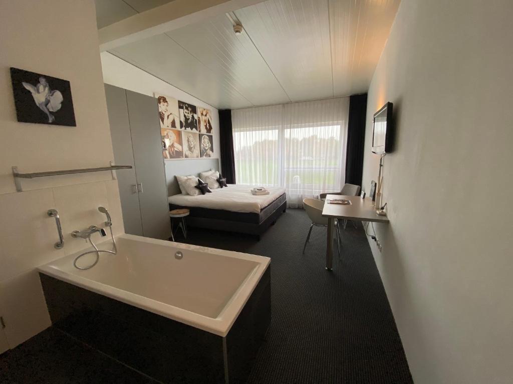 een badkamer met een bad en een bed in een kamer bij De Slaapfabriek vakantiehuis en trainingslocatie in Teuge