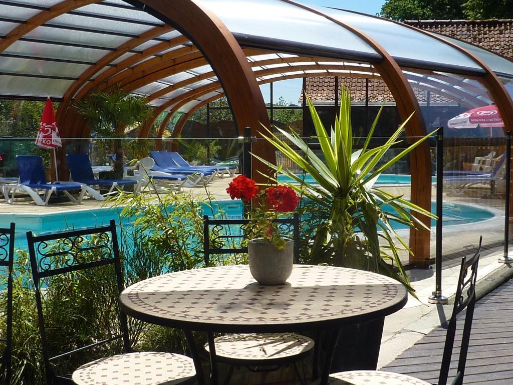 a table with a vase of flowers on a patio at Camping Pommiers des Trois Pays in Licques