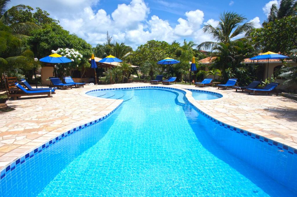 a swimming pool with blue chairs and umbrellas at Pousada Sol e Luna in Pipa