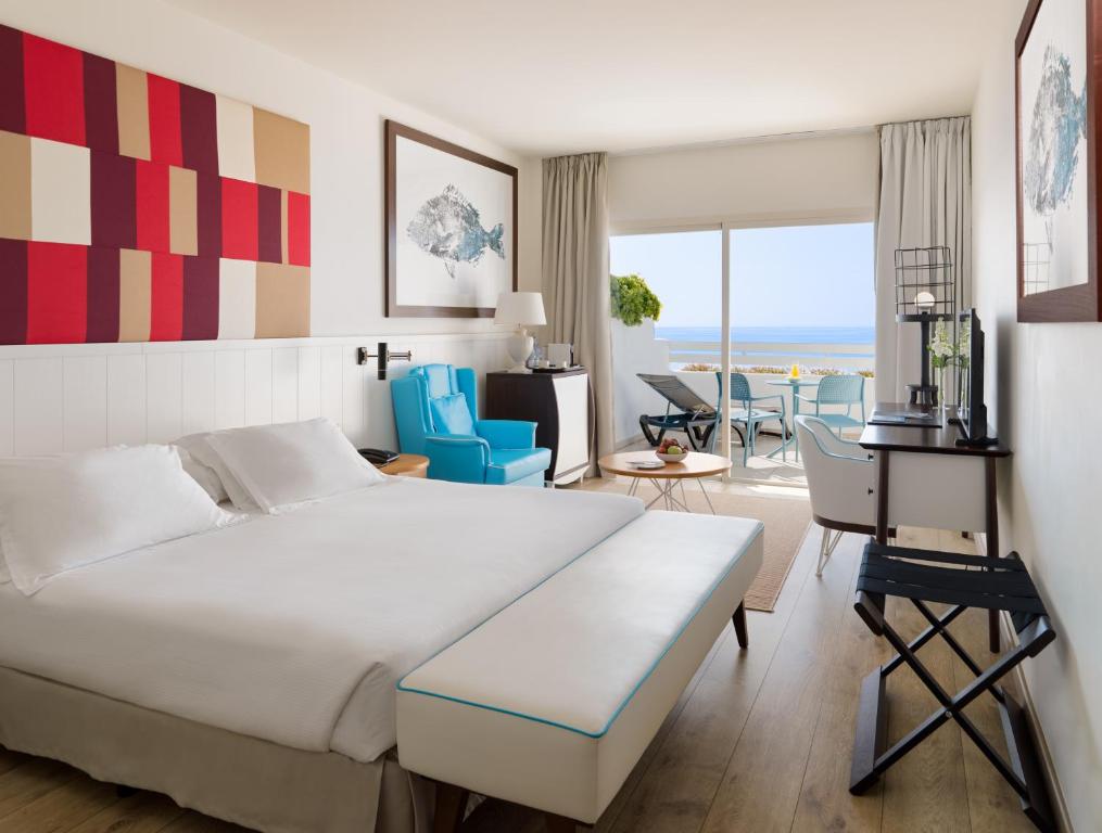 a hotel room with a bed and a desk and chairs at H10 Estepona Palace in Estepona