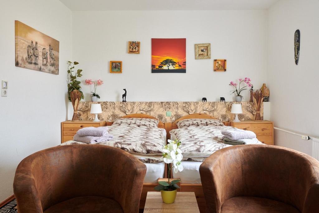 two beds in a room with two chairs at Hüblers-Schlafquartier in Fürstenwalde