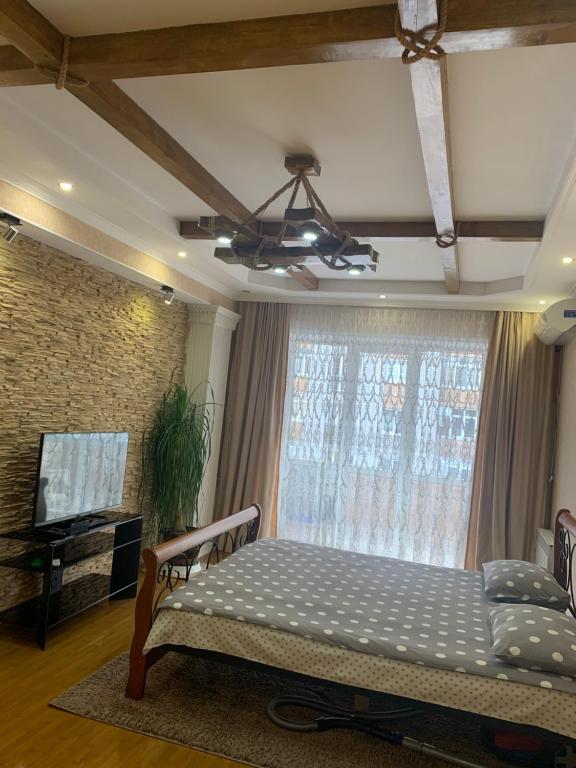 a bedroom with a bed and a window with a television at Apartment na Vladikavkazskoy in Vladikavkaz