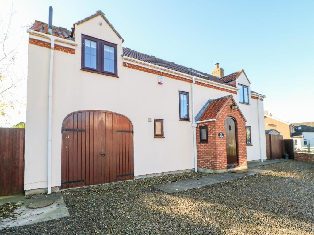 a white house with a brown door and a fence at Anvil Cottage in Northallerton