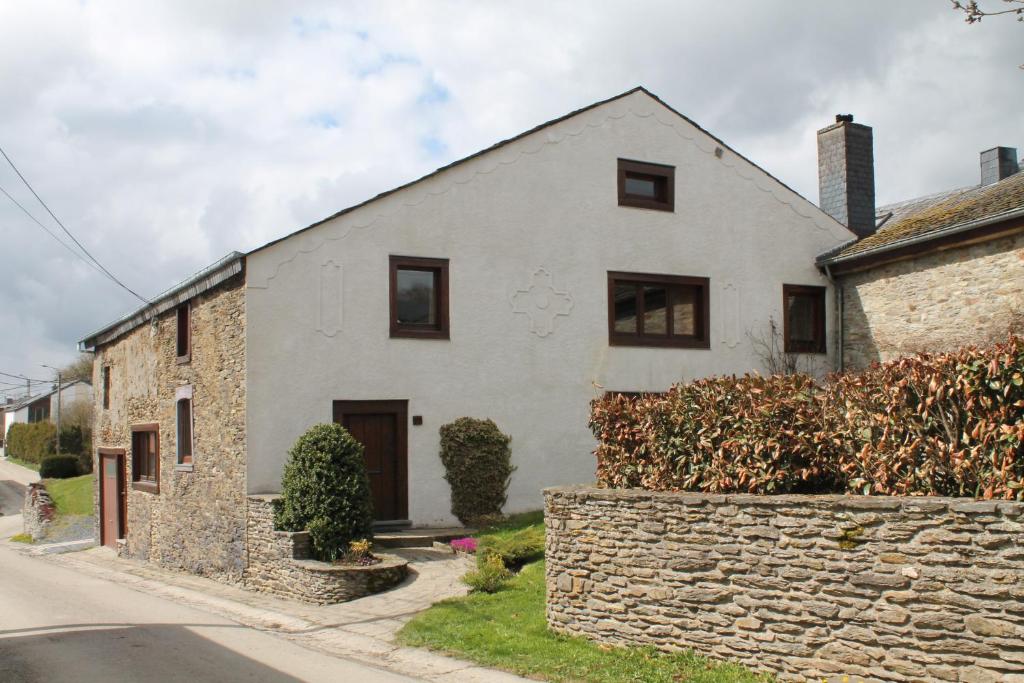 a white house with a stone wall at La Métairie in Houffalize