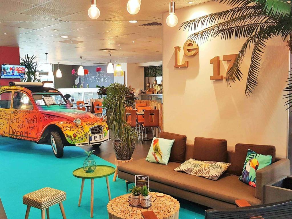 a room with a couch and a car on display at ibis Paris 17 Clichy-Batignolles in Paris