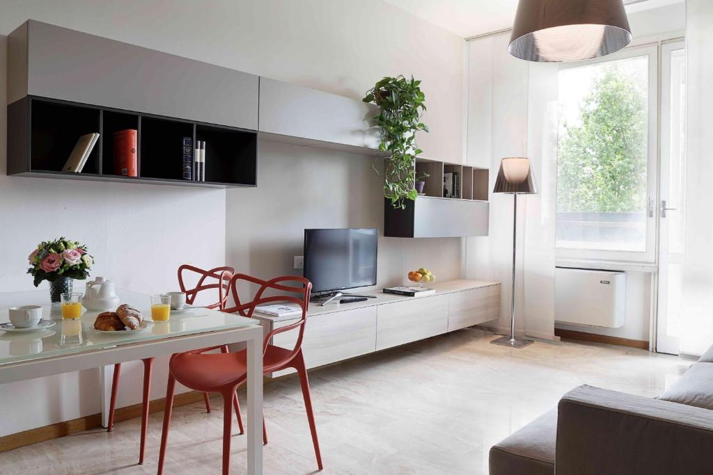 ein Wohnzimmer mit einem Tisch und Stühlen sowie einem TV in der Unterkunft Contempora Apartments - Elvezia 8 - E23 in Mailand
