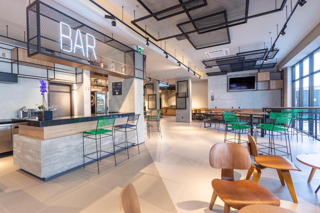 a bar in a restaurant with green chairs and tables at ibis Ponta Grossa in Ponta Grossa