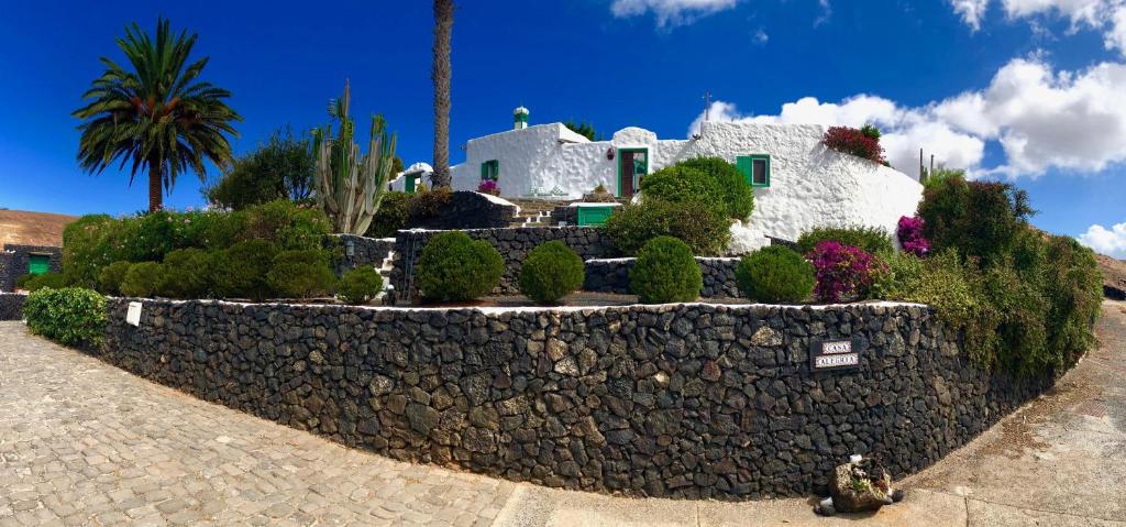 une maison avec un mur en pierre et des fleurs dans l'établissement Casa Alegría, à Los Valles