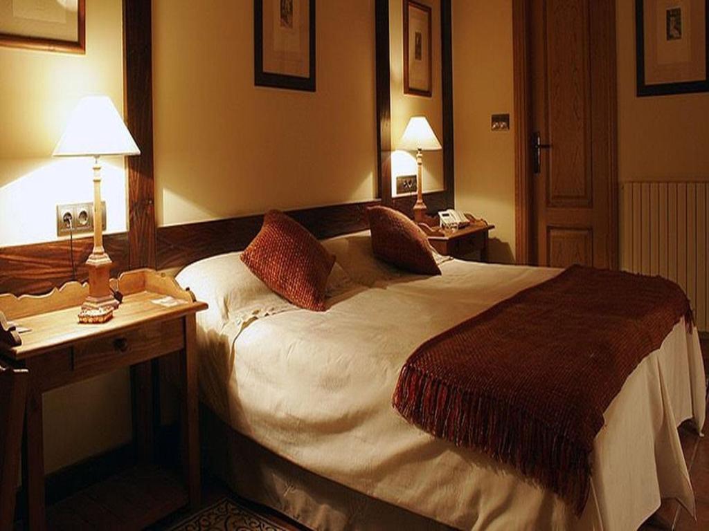a hotel room with a bed and a desk with two lamps at Hotel Casbas in Senegüé