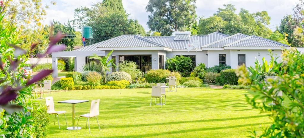 a white house with chairs and a yard at Sarum Lodge in Harare