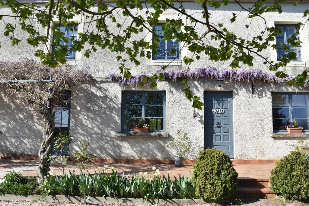 une maison blanche avec des glycines violettes sur la façade dans l'établissement Le Tilleul de Ray, à Ray-sur-Saône