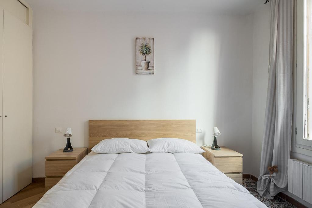 um quarto com uma grande cama branca com duas mesas de cabeceira em Cozy central apartment by Wonderful Italy em Bolonha