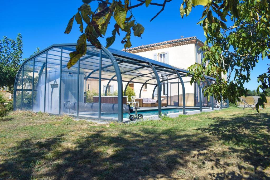 a glass greenhouse with a pool in a yard at La Grande Oasis - B&B et Spa in Grazac